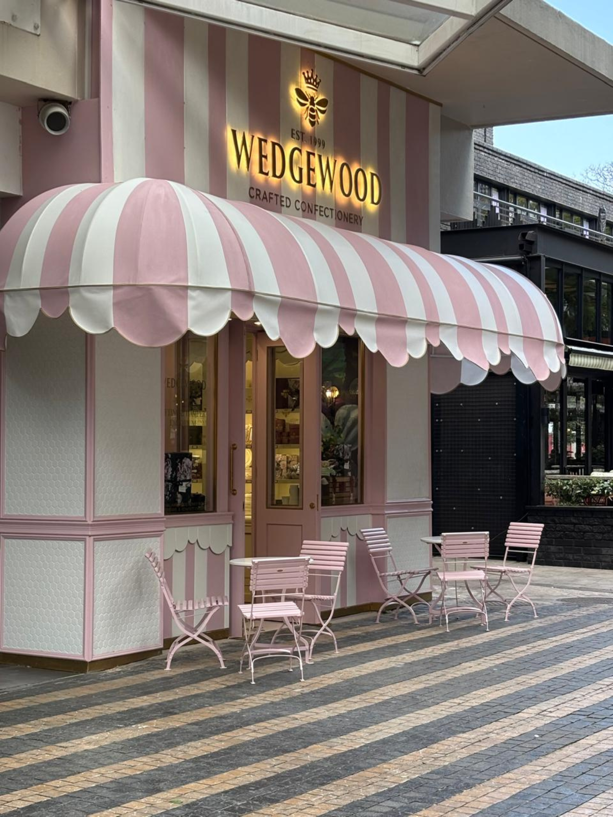 Wedgewood Rosebank store front with pink and white striped awning and outdoor seating area.